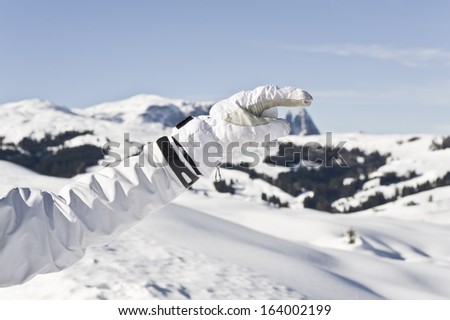 Human hand with ski glove over mountain peak