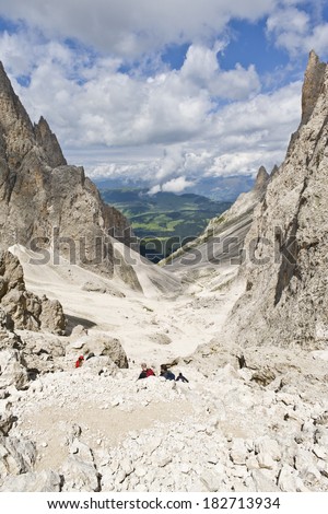 People climbing down Sasslong Mount, against clouds and blue sky, in the summertime