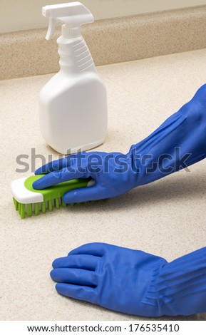 Scrubbing Kitchen Counter/ Vertical Shot/ Gloved Hands With Scrubber and Bottle/ Focus Is On The Gloved Hand With Scrubber
