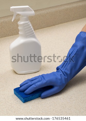 White Spray Bottle With Copy Space and Blue Rubber Gloved Hand With Blue Sponge/ Vertical Shot