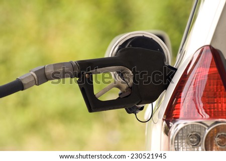 Horizontal Shot Of Gas Nozzle In Gas Tank Opening/ Buying Gasoline/ Shallow Depth Of Field