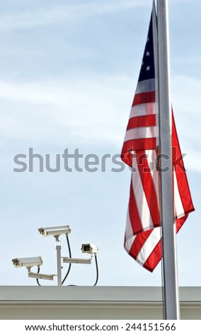 Vertical Shot Of Security Cameras With Out Of Focus American Flag