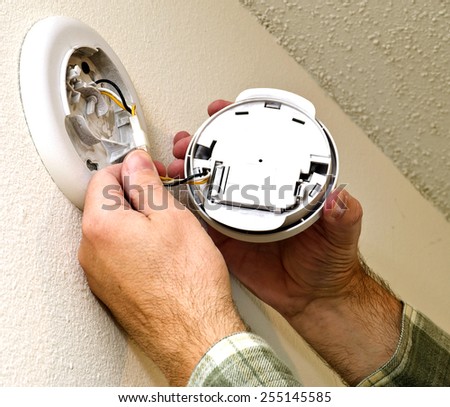Smoke Alarm Being Repaired On Wall / Time To Check Your Smoke Alarms