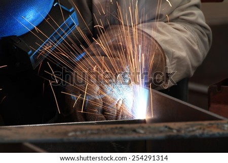 MIG-MAG welder welding steel part with all safety equipment