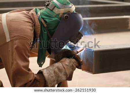 welder is welding end plate of steel pipe with all safety equipment in factory