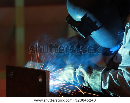 welder is welding steel structure with all safety equipment in factory