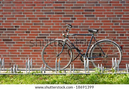 A bike leaning on a brick wall near a bike rack