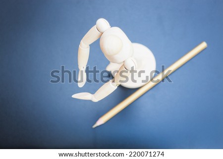 Wooden mannequin and pencil on dark background, stock photo