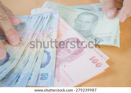 Man hand counting Thai baht banknote, stock photo