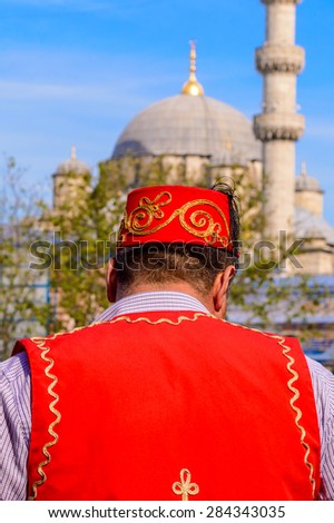 A turkish man dressed in traditional turkish costume in front of a mosque