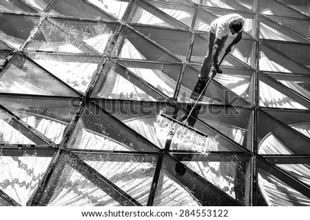 A man sweeping, washing and cleaning the glass roof of a restaurant