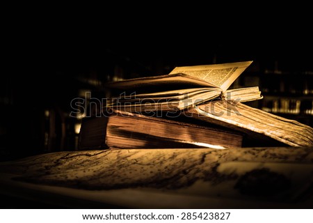 Old antique books on a library desk lit in the dark