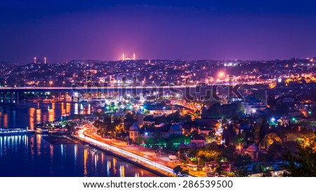 Istanbul city panorama at night, with colorful city lights, mosques and Golden Horn bay and a bridge over it.