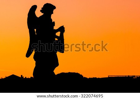 Sunset silhouette of an angel with the orange sky and copy space for text