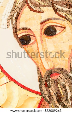 A detail of a face of a stone mosaic saint, with big eyes. Jesus Christ or John the Baptist.