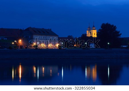 Evening dark landscape with historical architecture and lit church bell towers by the river