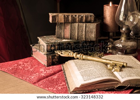 Artistic vintage style edit still life of old big brass key with old books, concept of the key of knowledge. Artistic selective focus.