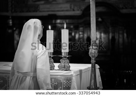 Artistic dark black and white edit of a catholic nun blowing the altar candles in a church