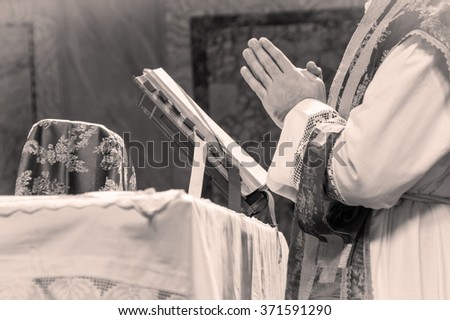 Artistic black and white dark vintage edit of a priest saying the extraordinary form, traditional latin tridentine rite Catholic mass. A detail.