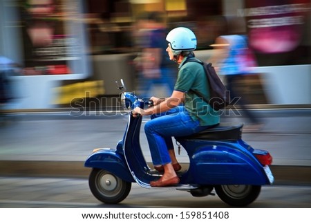 MILAN, ITALY - SEPTEMBER 12: Man rides scooter on September 12, 2013 in Milan. Italian Piaggio Group is the largest European manufacturer of two-wheel motor vehicles.