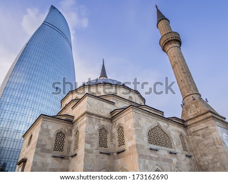 BAKU, AZERBAIJAN - NOVEMBER 22, 2013: The Mosque of the Martyrs (Sehidler Mescidi Mosque, Turkish Mosque) with the Flame Towers skyscraper in the background in Baku, Azerbaijan, at sunset. Horizontal