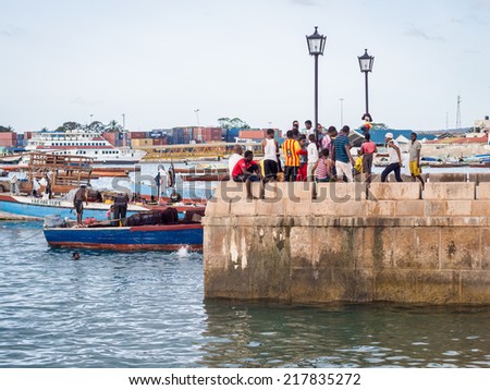 STONE TOWN - AUGUST 30, 2014: People in the port in Stone Town, Zanzibar on a weekend evening. The port is one of the tourist attractions of the city.