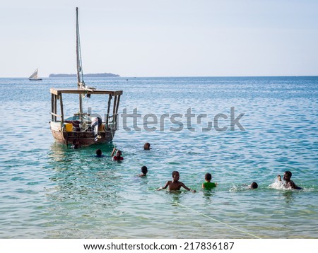 STONE TOWN - JULY 30, 2014: Kids playing in the water near to the port in Stone Town, Zanzibar on a weekend day. Zanzibar is a big tourist attraction of Tanzania.