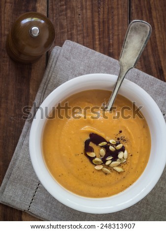 Vegan pumpkin cream soup with coconut cream, served with pumpkin seeds and pumpkin seed oil.