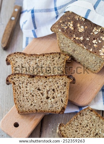 Homemade whole grain mixed rye-wheat sourdough bread with sunflower seeds and rolled oats, sliced. Vertical photo, overhead view, close up.