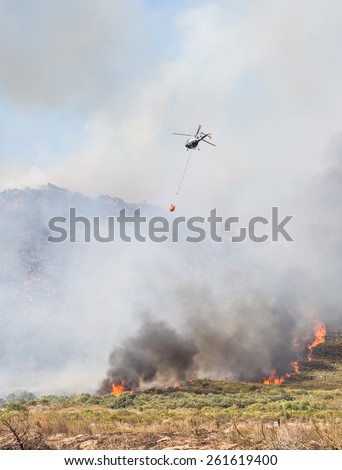 WESTERN CAPE, SOUTH AFRICA - FEBRUARY 17, 2015: Helicopter drops water over fire in Western Cape, South Africa, on a summer day. Fires are a common problem in Western Cape.