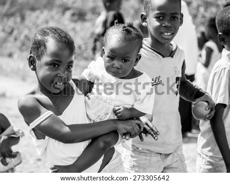 ZANZIBAR, TANZANIA - AUGUST 31, 2014: Local children asking people to take photos of them in one of the villages on Zanzibar island, Tanzania, East Africa. Horizontal orientation, black and white.
