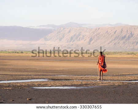 ARUSHA REGION, TANZANIA - OCTOBER 16, 2015: Maasai warrior wearing traditional red clothes in the dried part of Lake Natron in the North of Tanzania, Africa.