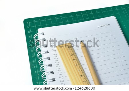 pen, ruler and notebook on cutting mat