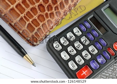 pen, calculator and purse on paper