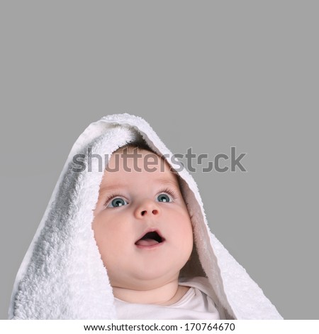 baby in white towel stares up gray eyes smiling