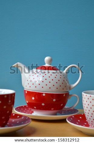 Red polka dot kettle and two cup of tea on wooden