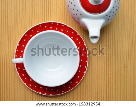 Red polka dot kettle and cup on wooden