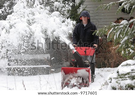 Man using a snow blower to clear a path after a storm