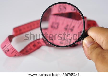 Hand Holding Magnifying Glass On Measure Tape, Focus on magnifying glass