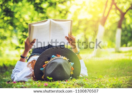 Asian woman travel nature. Travel relax. sleep Reading book On the lawn in the park. in summer.