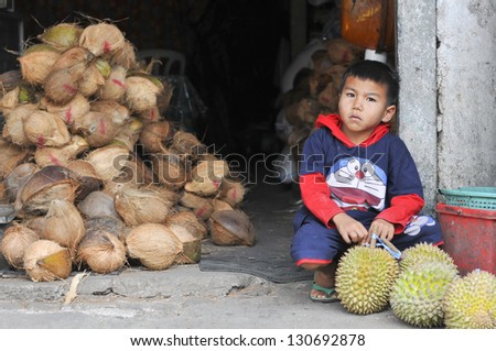 IPOH, MALAYSIA - SEPT 11: A Unidentified boy at a durian fruit stall on September 11, 2011 in Bazaar Baru Ipoh, Perak, Malaysia. Durian is revered in Southeast Asia as the King of Fruits.