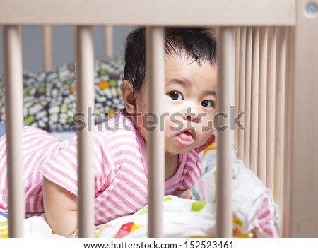 Cute baby gril lying in wooden crib or cot.