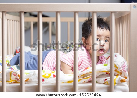 Cute baby gril lying in wooden crib or cot.