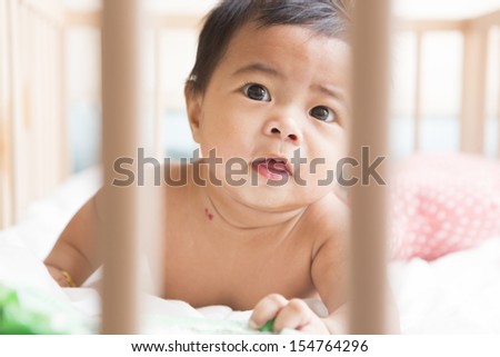 Cute baby gril lying in wooden crib or cot