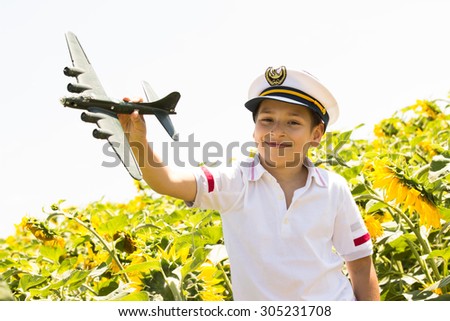 Happy kid playing with toy airplane against blue summer sky background