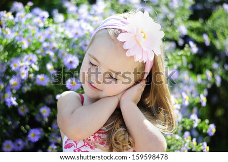 pretty little girl near a bush of flowers