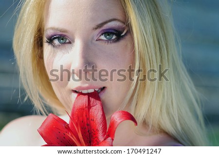 beautiful girl blonde near lake with red flower