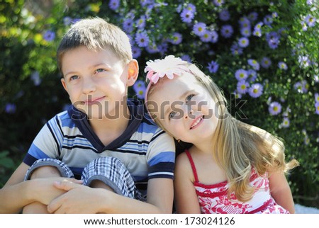 a couple of boy and girl sitting near flowers