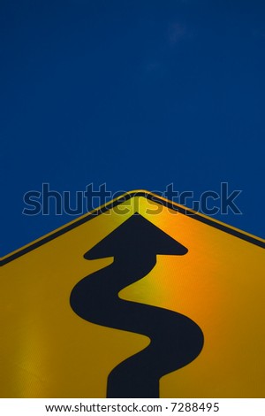 Winding way up to success. Yellow road sign against blue sky