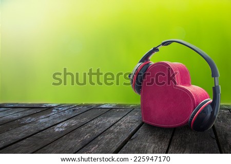 Headphones with red  heart on wood table. music of love. vintage retro